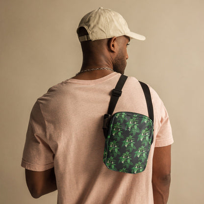 Utility crossbody bag with green leaf floral print, worn on back with black strap