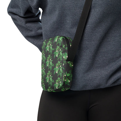 Utility crossbody bag side view in green leaf floral print on dark fabric
