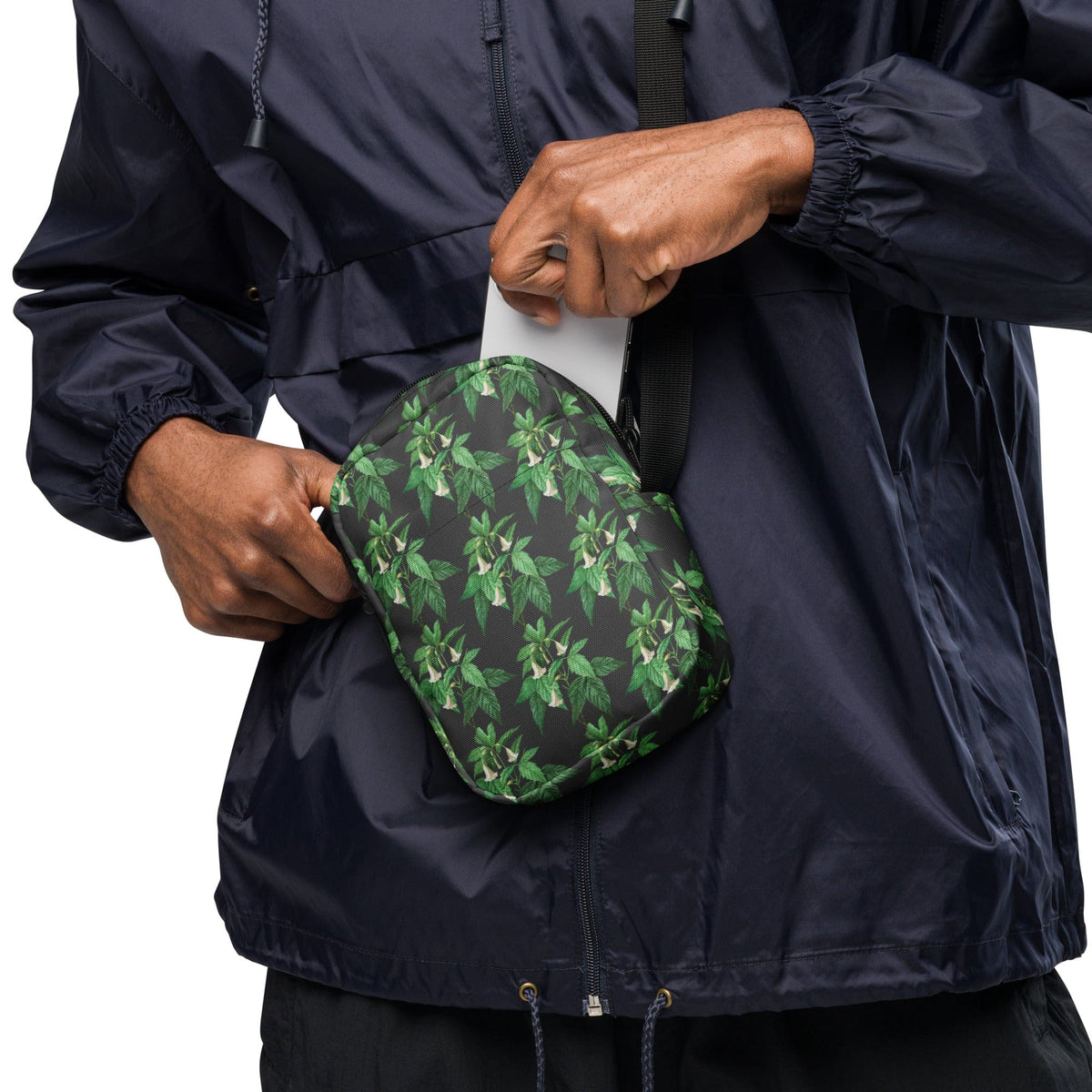 Utility crossbody bag held up, green leaf floral print on dark fabric
